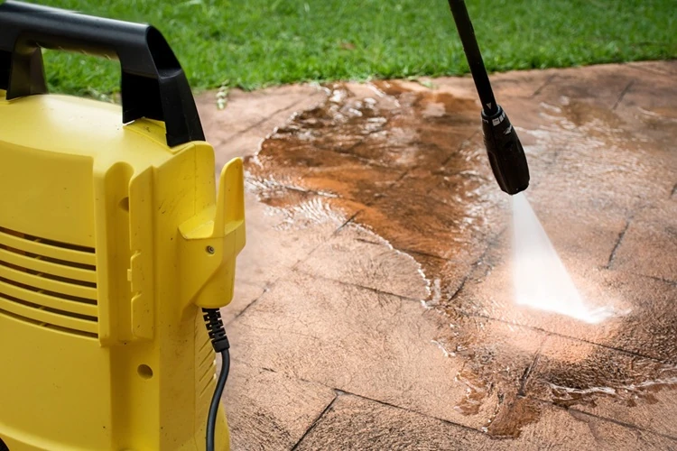 lawnmax-Pressure-Cleaning-500px Yellow pressure washer cleaning dirt off a paved patio area with a strong water spray.