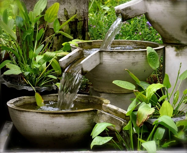 cascading-garden-water-feature Decorative garden water feature with cascading water flowing between ceramic bowls surrounded by plants