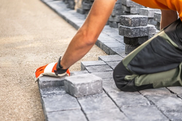 lawnmax-carefully-positions-paving-stones-on-roadbase Lawnmax wearing gloves laying paving stones to build a pathway or patio area