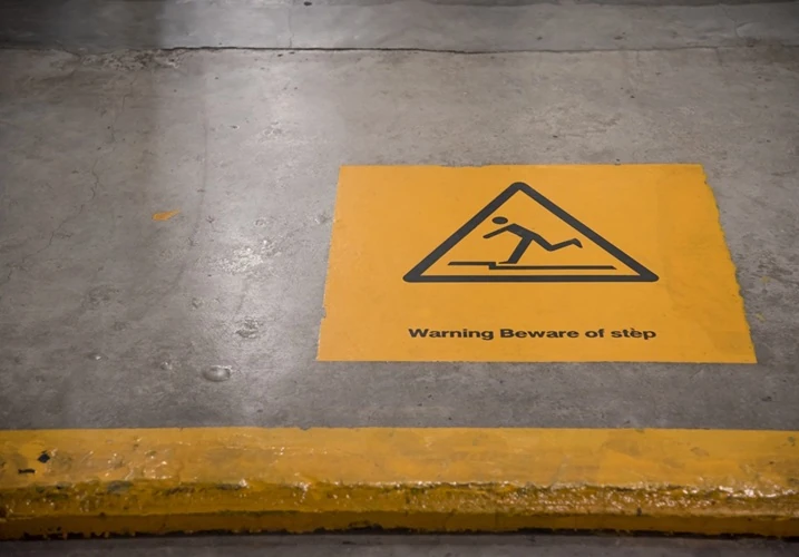 warning-beware-step-500px Yellow warning sign on concrete floor cautioning about a step hazard with text "Warning Beware of step"